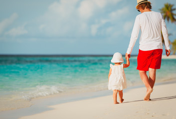 father and little daughter walk on beach