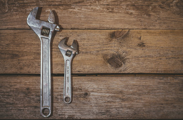 Two wrenchs, big and little on wooden background