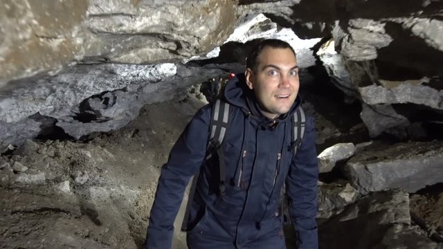 Male Traveler Walking Through Tight Tunnel inside Cave