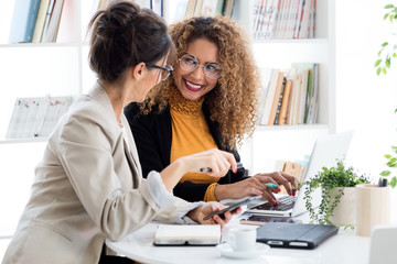 Two businesswoman working with laptop in her office.