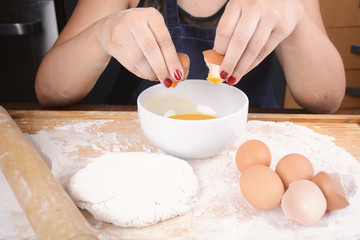 Woman breaking an egg into bowl.