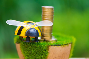 Stack of gold coin on artificial grass in pot, on wooden table with green nature background. vintage tone.