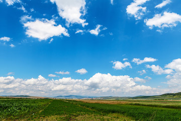 Small city by the mountains under blue cloudy summer sky, somewhere in Romania