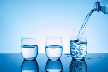 Bottle with creative splashing water in the glass