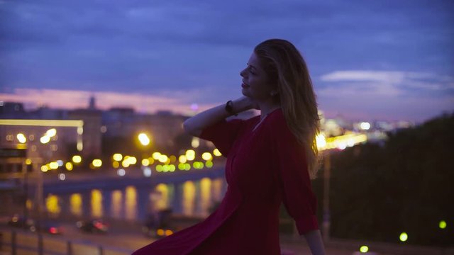 Young woman in red dress is sitting on a parapet