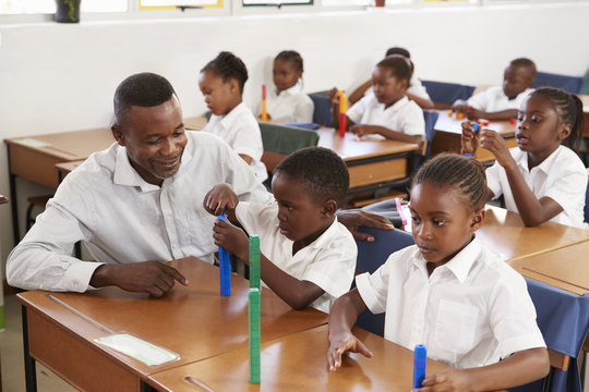 Teacher Helping Elementary School Kids Counting With Blocks