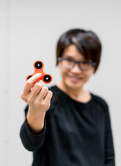 Asian woman holding oragne fidget spinner