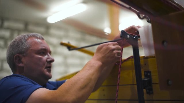 Mature master in spectacles with assistant working with homemade sailboat in workshop 4k. Teal and orange style. Close-up. Big hobby concept