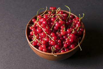 Fresh red currants in plate on dark  wooden table.