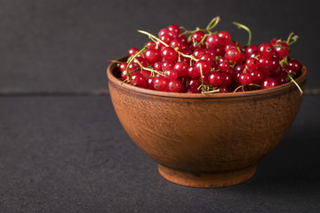 Fresh red currants in plate on dark  wooden table.