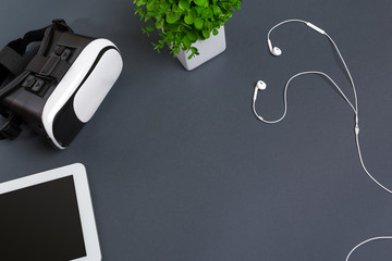 Virtual reality glasses and tablet with headphones on a gray background. Top view