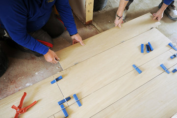 Two construction workers placing a porcelain stoneware pavement that imitates beech wood
