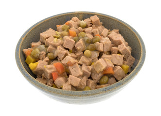An old stoneware bowl filled with lamb dog food isolated on a white background.
