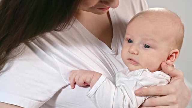 Tilt up of affectionate mother holding lovely baby boy on arms 