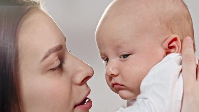 Slow motion of young mother lifting up her baby and tenderly kissing him