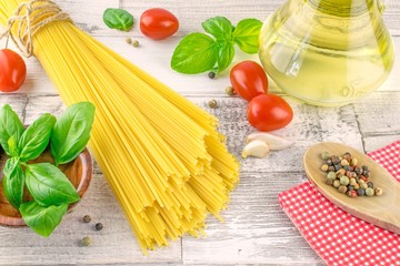 Italian spaghetti pasta and fresh ingredients on a rustic wooden background