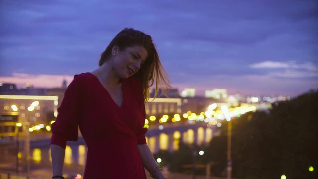 Young woman in red dress is standing near parapet