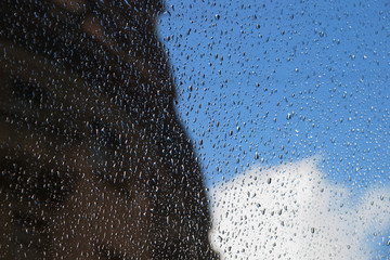 Drops of rain on the window, sky, cloud and silhouette of the building
