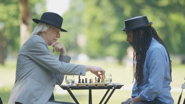 Two old friends in a park shake hands after a game of chess