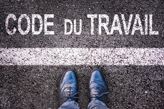 Code du travail (meaning labor code in French) written on an asphalt road background with legs