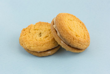 Two sugar cookies with hazelnut filling on a blue cloth napkin.