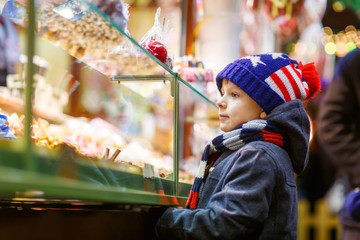 Little kid boy with gingerbread and sweets stand on Christmas market