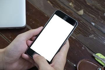 Close up of Business man holding smartphone with blank screen mobile on wooden desk in coffee shop.