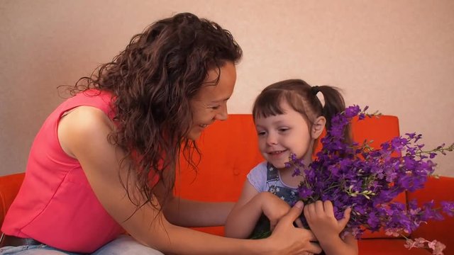 Mom gives flowers to her daughter. Mom gives the child wild flowers.