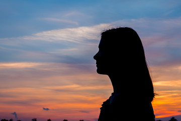 Girl enjoys the sunrise with a view of the beautiful sky. Portrait in profel.