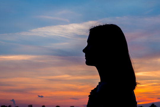 Girl enjoys the sunrise with a view of the beautiful sky. Portrait in profel.