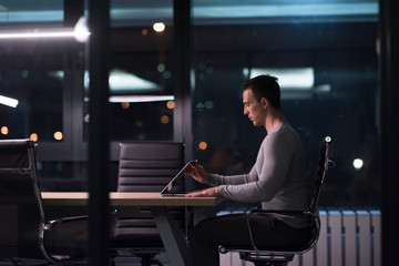 Plakat man working on laptop in dark office