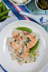 Oriental dish with chicken, shrimps and vegetables. White plate, blue wooden table.
