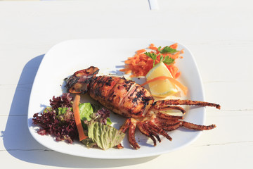 Grilled squid served by the sea in Greece, Traditional greek dish on the white wooden table background