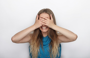 Fototapeta premium Headshot of young adorable blonde woman with cute smile on white background covers her face with palms