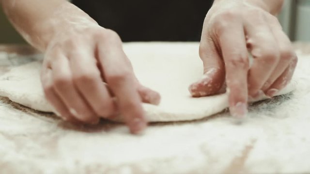 Italian pizza preparation. Woman baker kneading uncooked dough in the kitchen.   