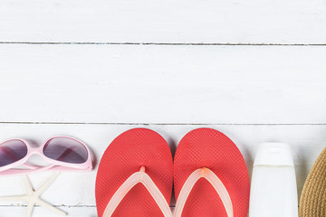 Beach accessories. Bag, towel, sunglasses and flip-flops on wooden background. Top view with copy space