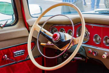 The wheel of an old retro car with red velvet padding inside