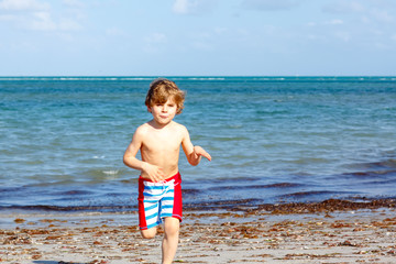 Fototapeta na wymiar Little kid boy having fun on tropical beach