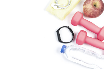 sport, healthy lifestyle and objects concept - close up of dumbbells, fitness tracker, earphones and water bottle over white background