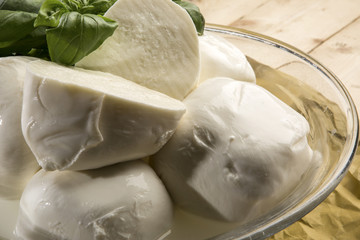 mozzarella di Bufala e tagliata a metà e basilico fresco dentro ampolla di vetro sopra carta da cucina e tavolo in legno