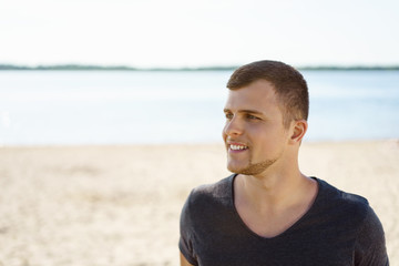 Fototapeta na wymiar Smiling young man relaxing on a beach