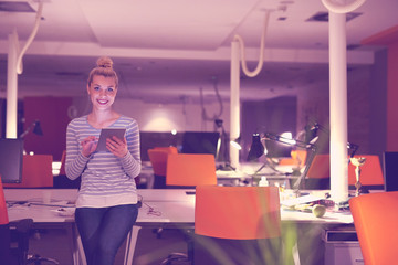 woman working on digital tablet in night office