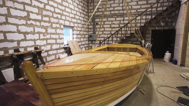 Wooden boat with sail mast within workshop. steadicam shoot. Homemade Sailbaot ready to move in sea, lake, or river. Big hobby concept. Close-up