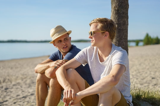 Two young men relaxing on the beach together