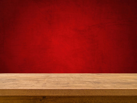 Empty wooden table on red textured background