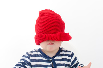 Baby in a red hat pulled over his face studio