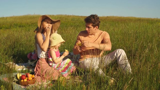 little girl feeds her daddy a pineapple at a picnic