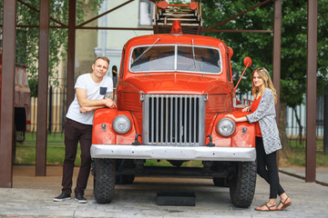 Vintage firefighting truck and a couple in love. Outdoor portrait of a beautiful young white girl...