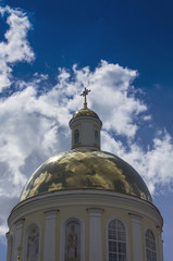 Temple of Orthodox Christians with a gold cupola against a blue sky with white clouds.