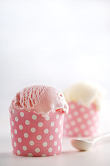 Vanilla and strawberry ice cream in a pink cup on a white background. Copy space